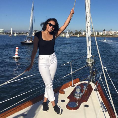 Pisay Pao in black t-shirt and white pant poses at a boat. 