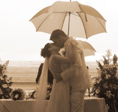A man and woman kissing at the beach.