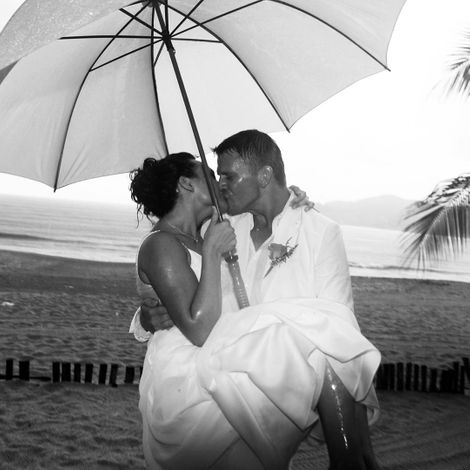 A man and woman Kissing under an umbrella.