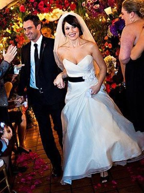 Marla Sokoloff and her husband, Alec Puro walking down the hallway of their wedding venue while holding hands.