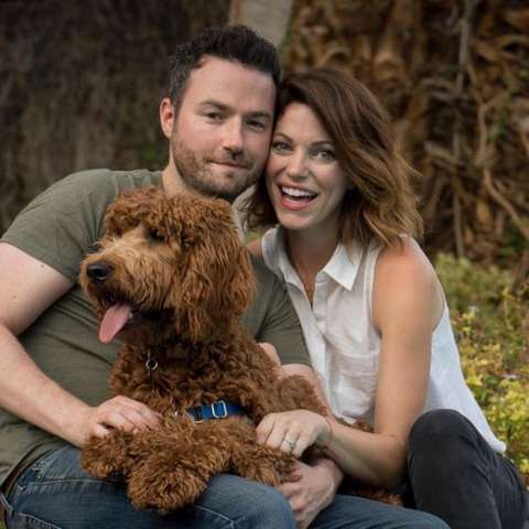 Courtney Henggeler and her husband Ross holding their doodle dog.