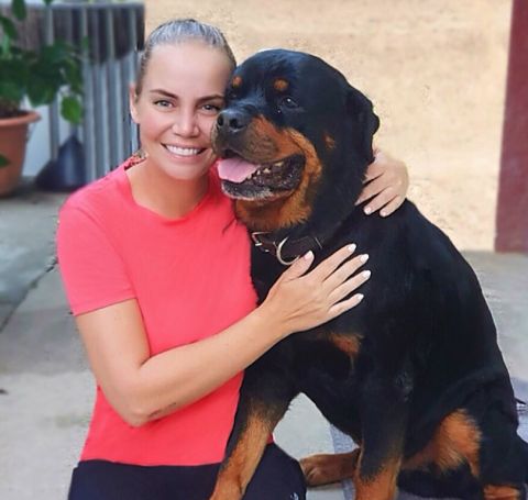 Jelena Dokic in a pink t-shirt with a husky black dog.