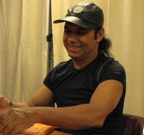 Bikram Choudhury in a black t-shirt and black cap.
