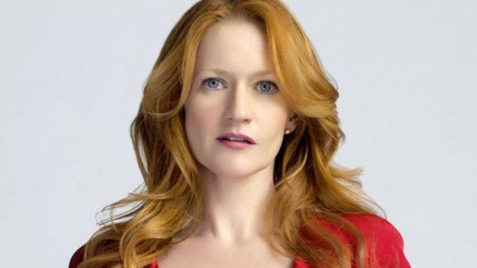 Paula Malcomson with auburn hair and blue eyes wearing a red dress.