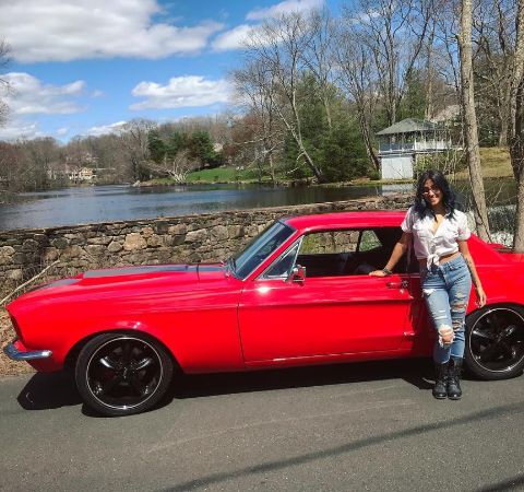 Krystle Amina with her red Ford Mustang pose for a picture.