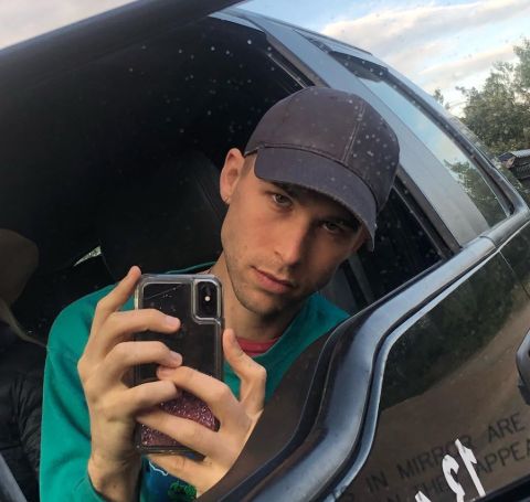 Tommy Dorfman poses for a picture outside his car.