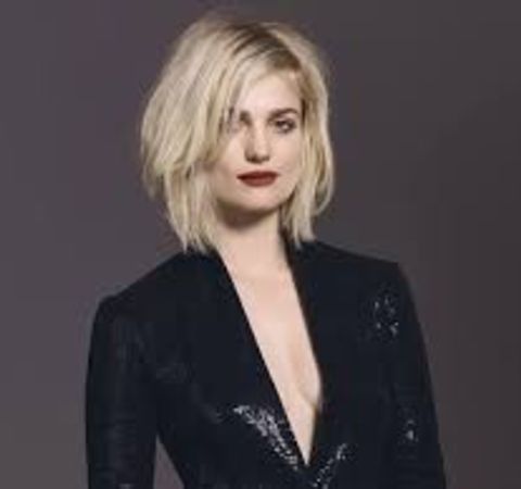 Alison Sudol in a black coat poses at a photoshoot. 