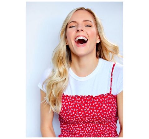 Kari Perdue in a white-red dress laughing at the camera.