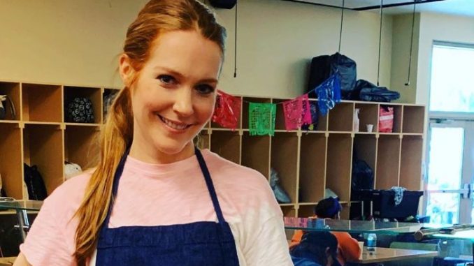 Darby Stanchfield in a pink t-shirt and blue apron poses for a picture.