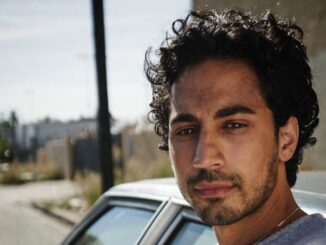 Andres Joseph poses a picture in front of a car.