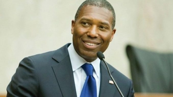 Tony West in a black suit poses for a picture.