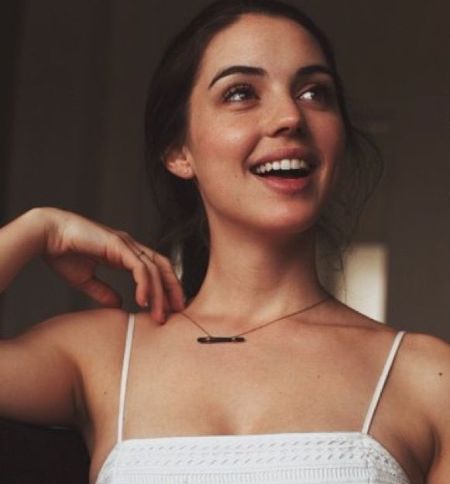 Adelaide Kane in a white top poses for a picture.