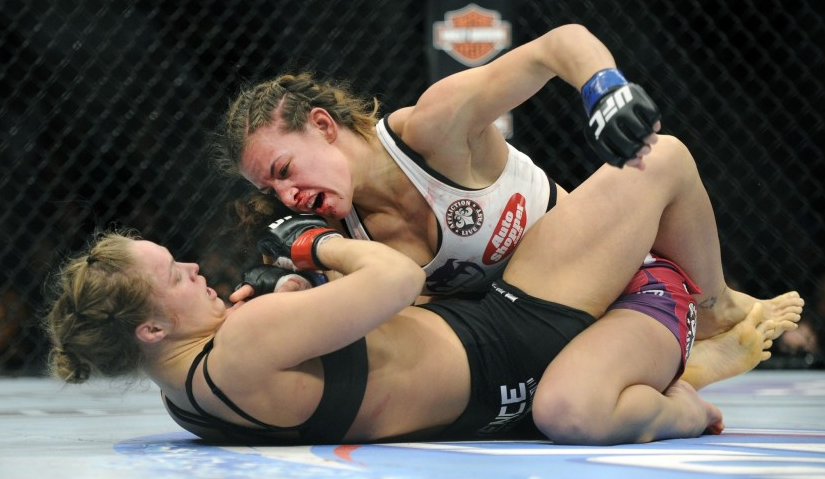 Miesha Tate punches Ronda Rousey during their bantamweight title fight at UFC 168 in Las Vegas