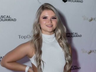 Taylor Kamphorst wearing white dress and posing for a photo at an event.