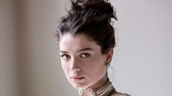 Eve Hewson wearing a white dress and posing for a photo.