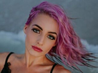 Moriah Plath wearing a black top and posing for a photo on a beach.