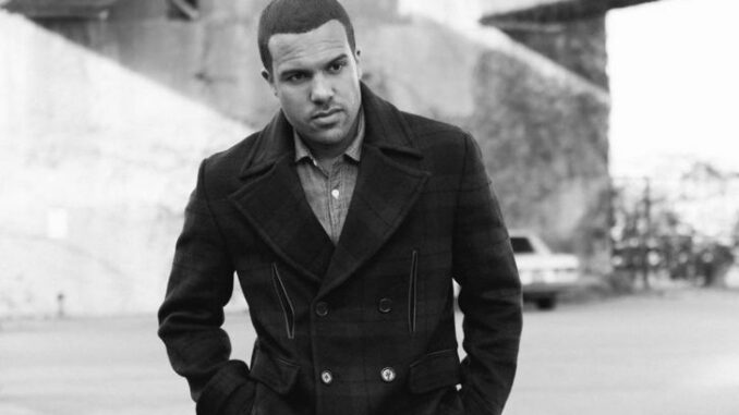 O. T. Fagbenle wearing a black overcoat and posing for a photo.