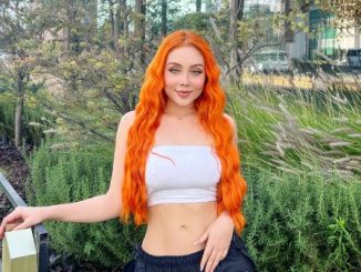 Maya Nazor with hair dyed orange on white top and black bottom.